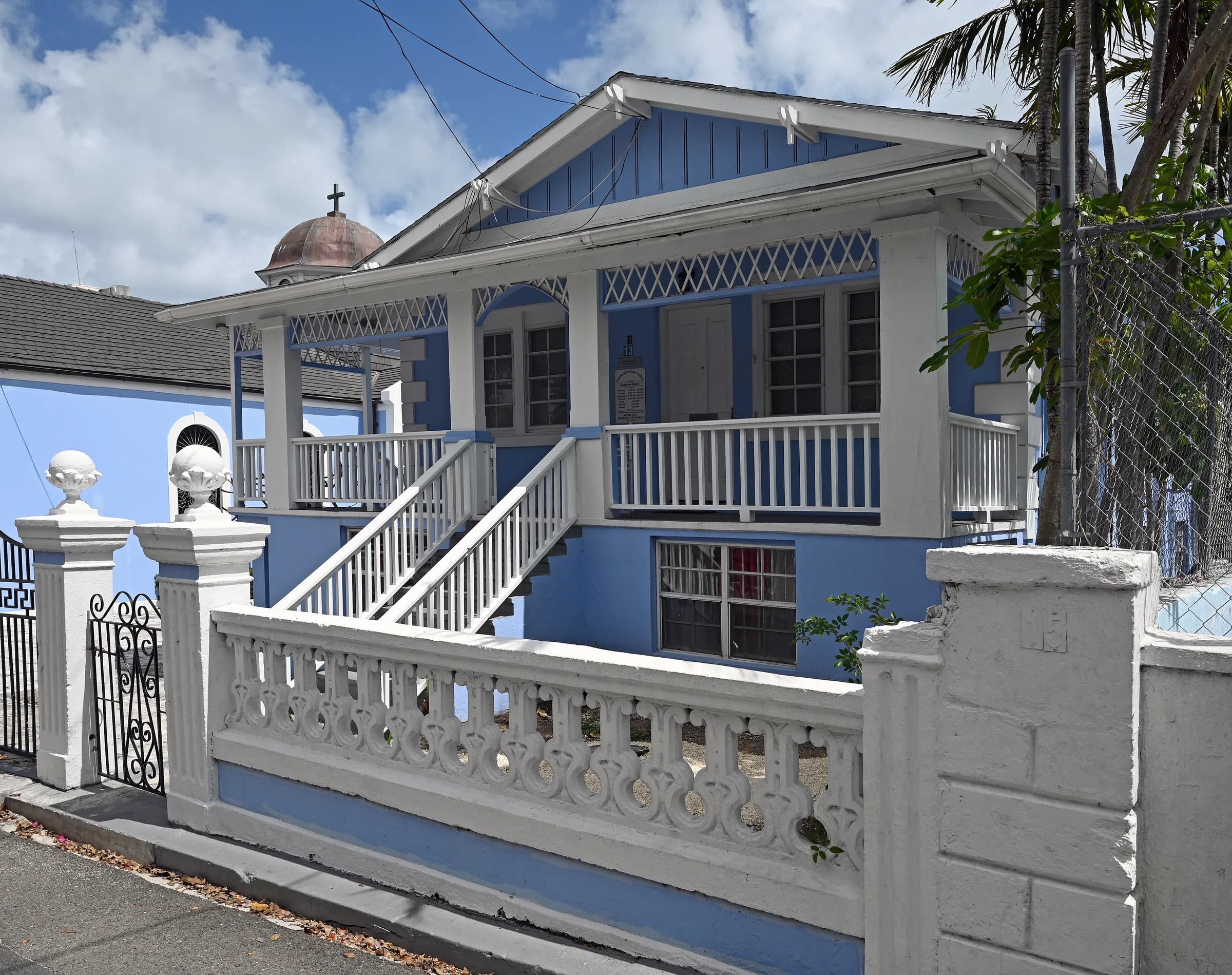 Blue two-storey house with a white veranda and front steps in Nassau